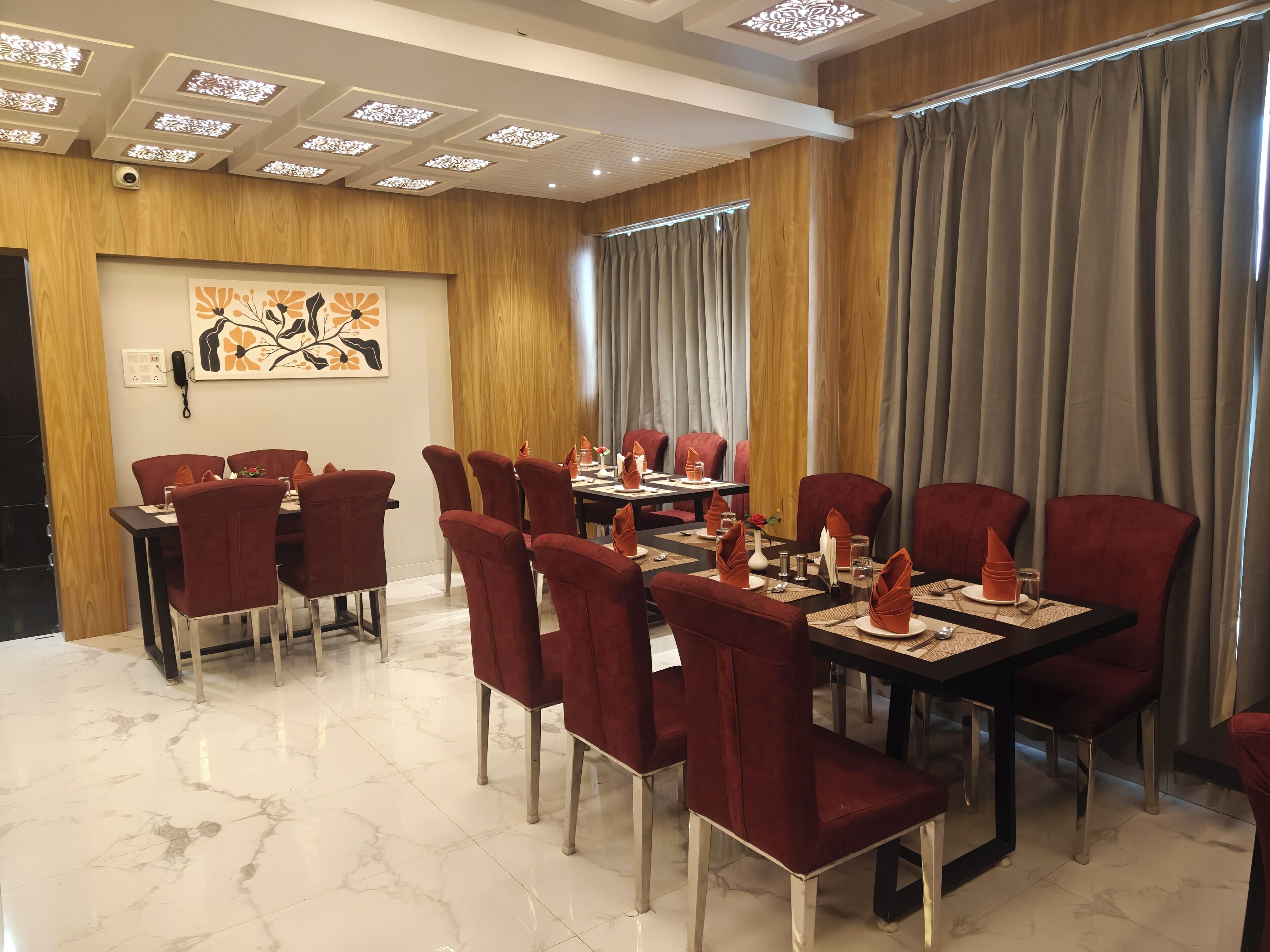 Un salón de conferencias con suelo de mármol, sillas tapizadas en rojo y una pared revestida de paneles de madera.