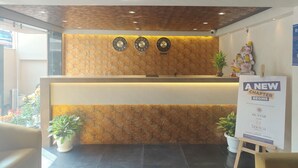 A hotel reception area with a wooden textured wall, three clocks, and a sign announcing a new chapter. - Hotel Teesta Stays Kolkata (Barasat)