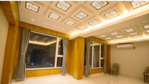 A spacious room with large windows, wooden paneling, and a decorative ceiling. - Hotel Teesta Stays Kolkata (Barasat)