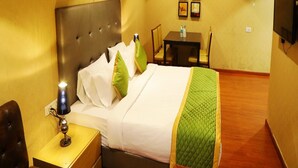 Ein Hotelzimmer mit Bett, Nachttisch, Lampe und Fernseher an der Wand.
