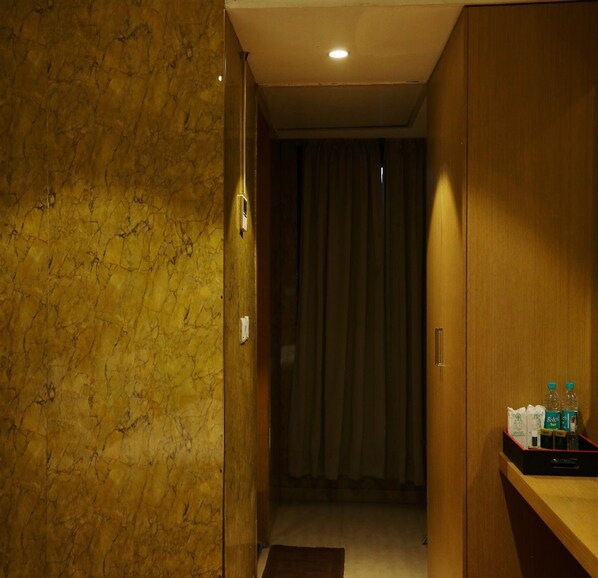 A hotel room with a marble wall, a wooden door, and a small table with toiletries.