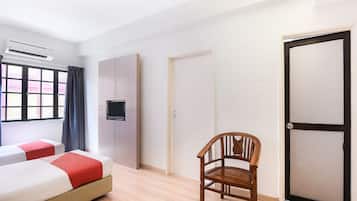 Habitación de hotel con dos camas, una silla de madera, un armario y una puerta.