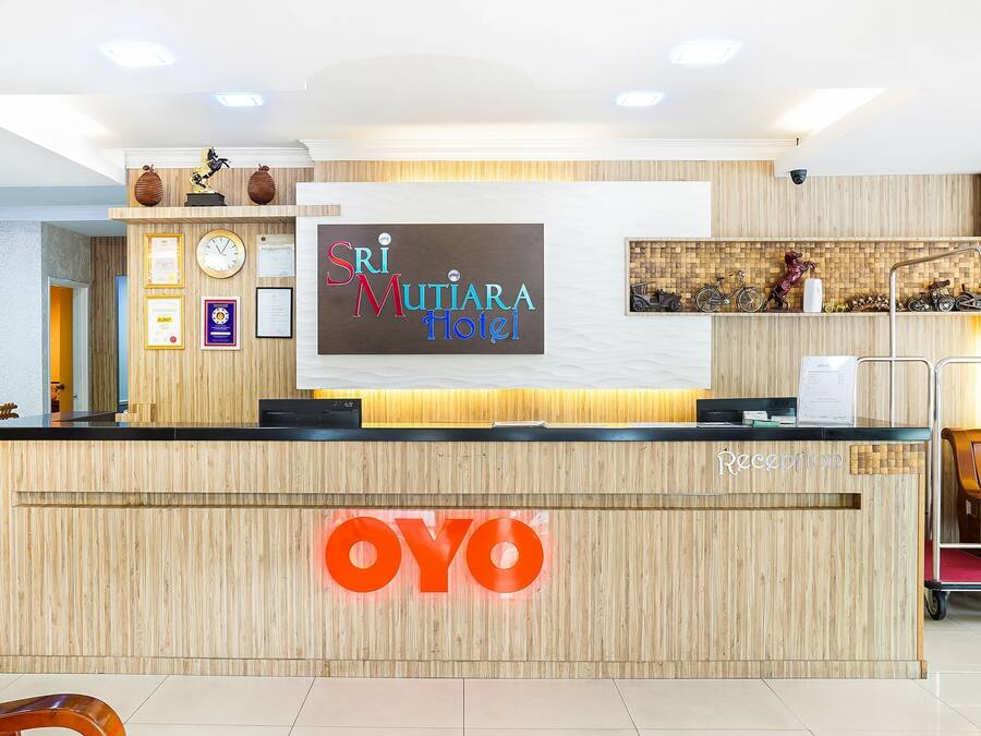 A reception desk with a wooden finish and a large illuminated 'OYO' sign.