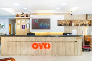 Un comptoir d’accueil avec un revêtement en bois et un grand panneau lumineux portant l’inscription « OYO ».