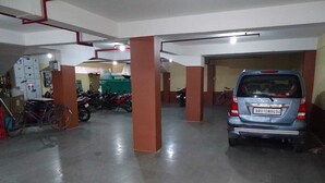 A parking garage with a blue car and several motorcycles.