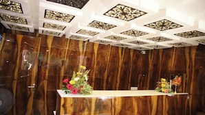 A reception area with a wooden panel wall, a reception desk, and a ceiling with decorative patterns.