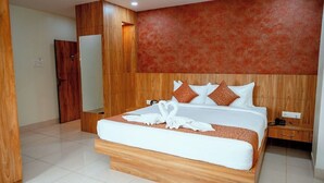 A modern hotel room with a large bed, wooden headboard, and a red textured wall.