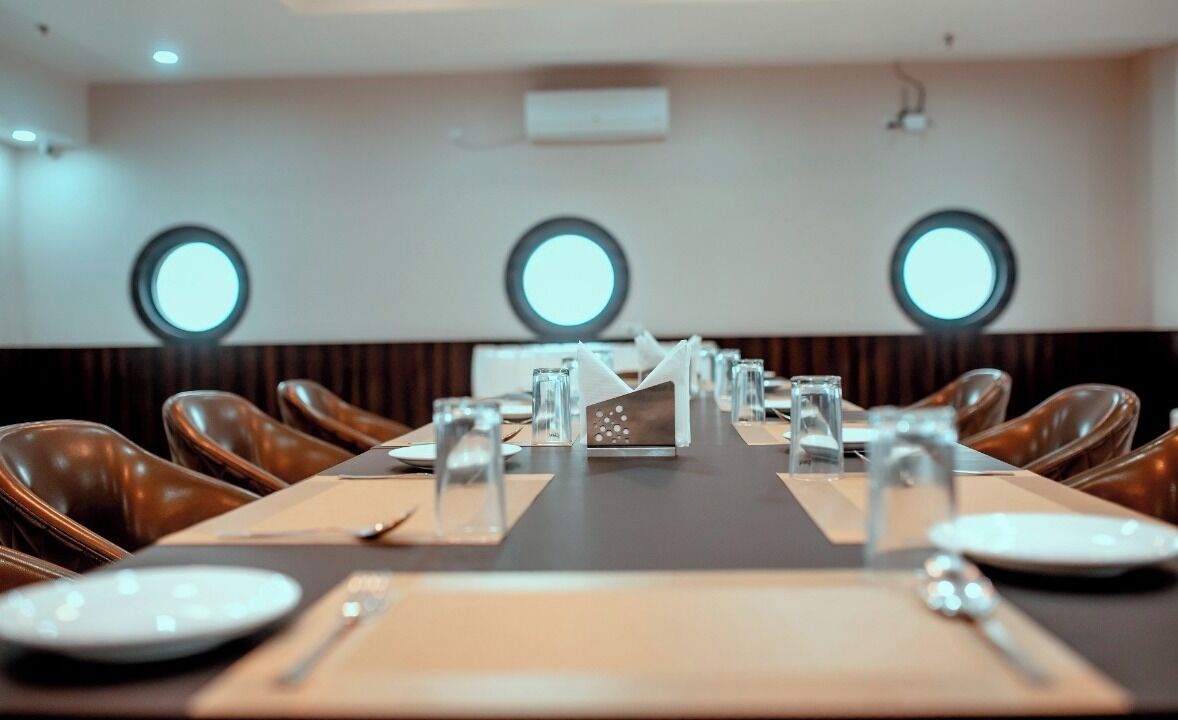 A conference room with a long table, chairs, and round windows.