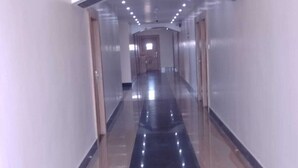 A long, narrow hallway with a shiny black floor and white walls.