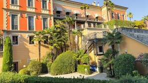 Un immeuble à plusieurs étages doté de balcons, de palmiers et d’un jardin bien entretenu.