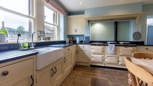 Een keuken met witte kastjes, een zwart aanrecht en een betegelde spatwand.