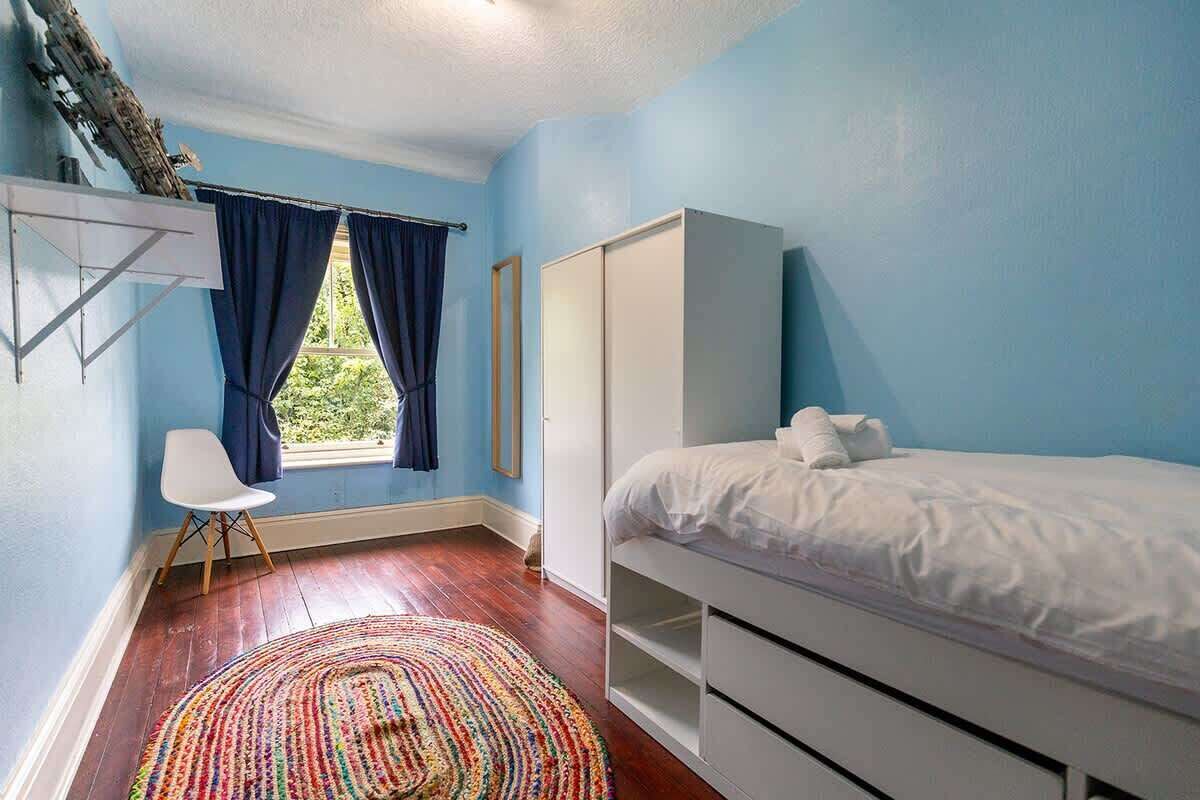 A bedroom with a bed, wardrobe, and a window with curtains.