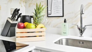 Cocina moderna con salpicadero de mármol, un lavabo, una cesta de frutas y un menú enmarcado.