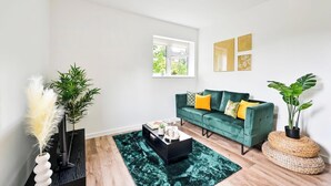 Una sala de estar moderna con un sofá verde, una mesa de centro y plantas decorativas.