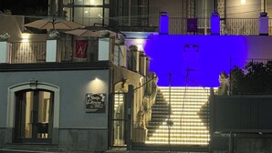 A building with a staircase leading to a second floor, a sign for 'Stanze Stellerane', and outdoor seating with umbrellas. - Stanze letterarie  (Catania)