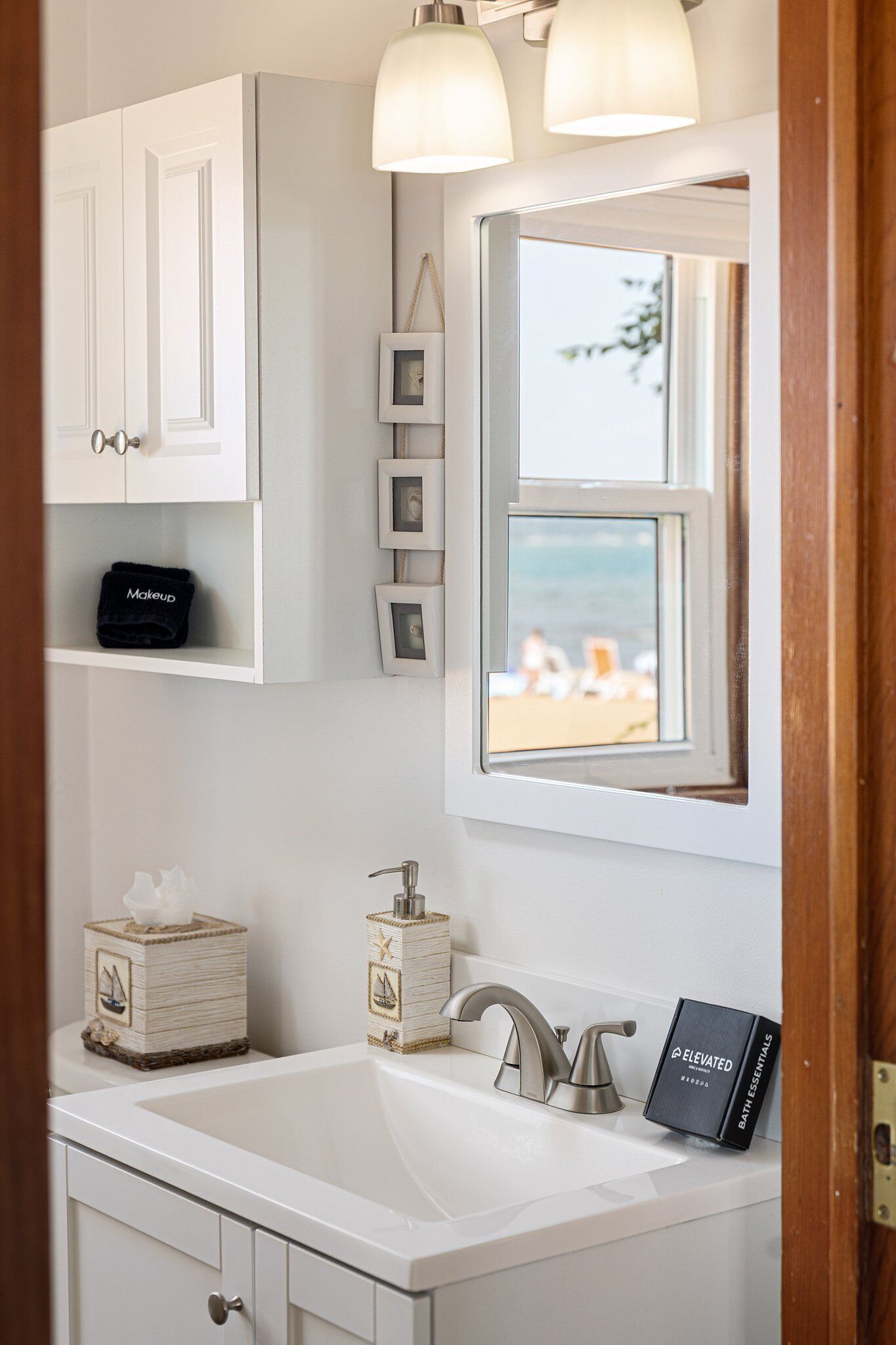 Un baño con lavamanos, tocador y ventana con vista a la playa.