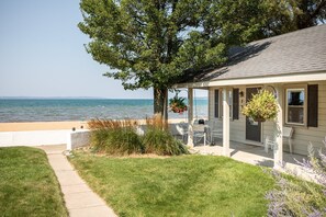 A house with a covered porch, a view of the sea, and a well-maintained lawn. - Lucky #7 @ Lakeshore Resort (Traverse City)