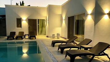 A modern outdoor pool area with lounge chairs and a pool.