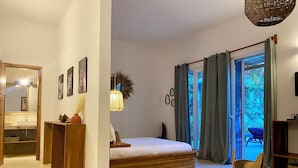 Un dormitorio con cama, una mesita de noche de madera, un espejo y vistas al exterior a través de una puerta corredera.