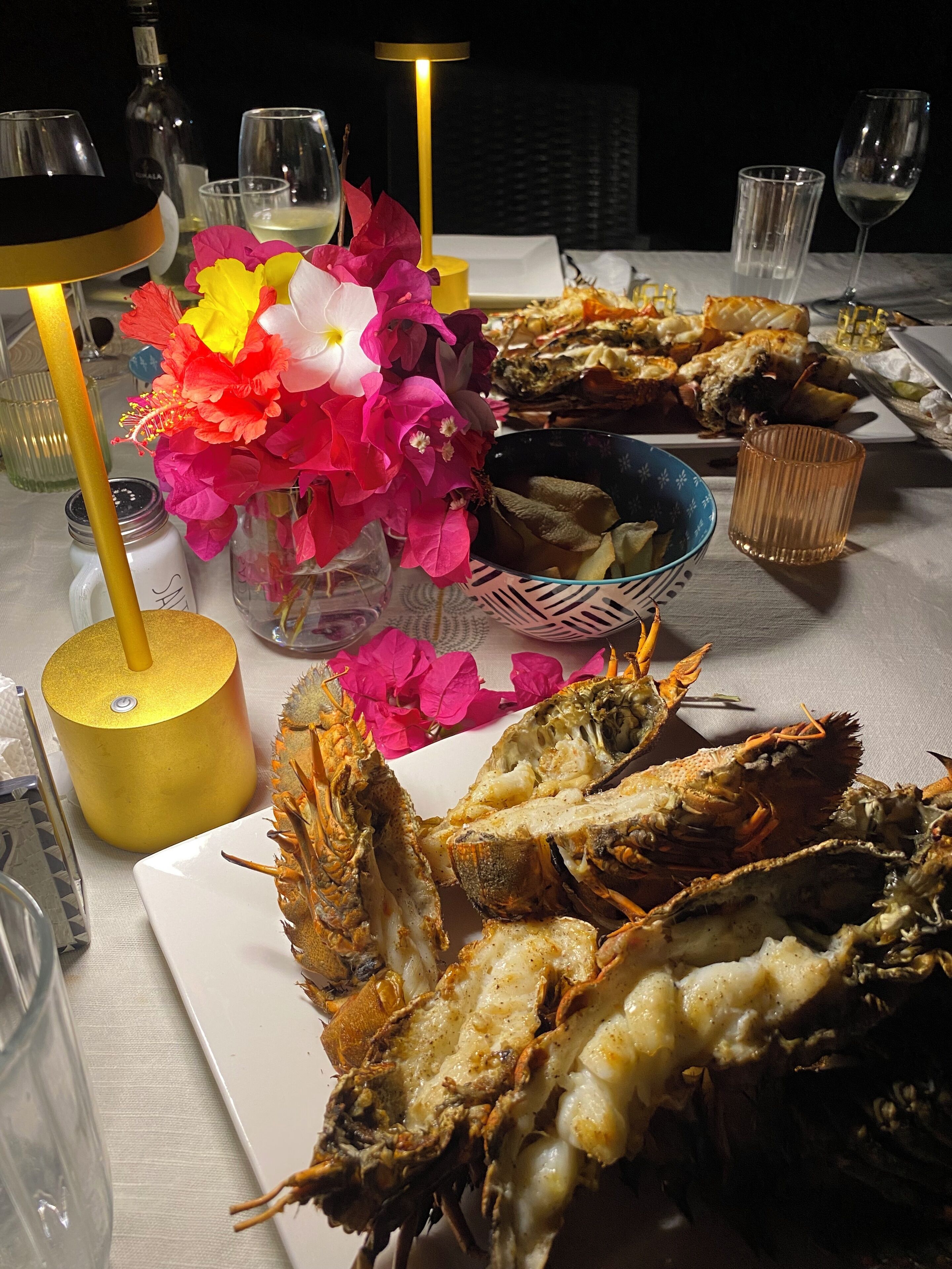 A dining table with seafood, including lobsters, and a vase of flowers.