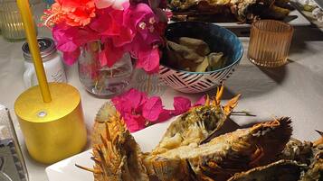 A dining table with seafood, including lobsters, and a vase of flowers.