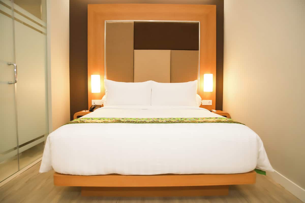 A modern hotel room with a large bed, wooden headboard, and bedside lamps.