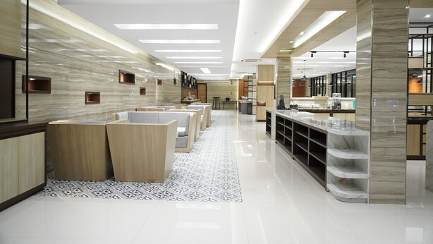 A modern hotel lobby with a reception desk, seating area, and a counter with display cases. - Front One Hotel Papua Lestari (Timika)