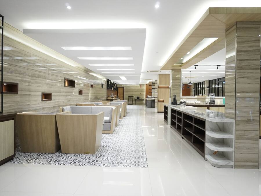 A modern hotel lobby with a reception desk, seating area, and a counter with display cases.