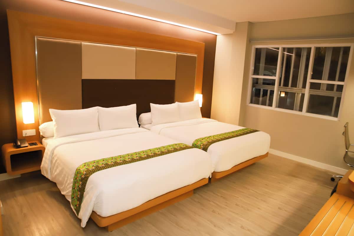 A double bed with a wooden headboard, two bedside tables with lamps, a window with blinds, and a wooden floor.