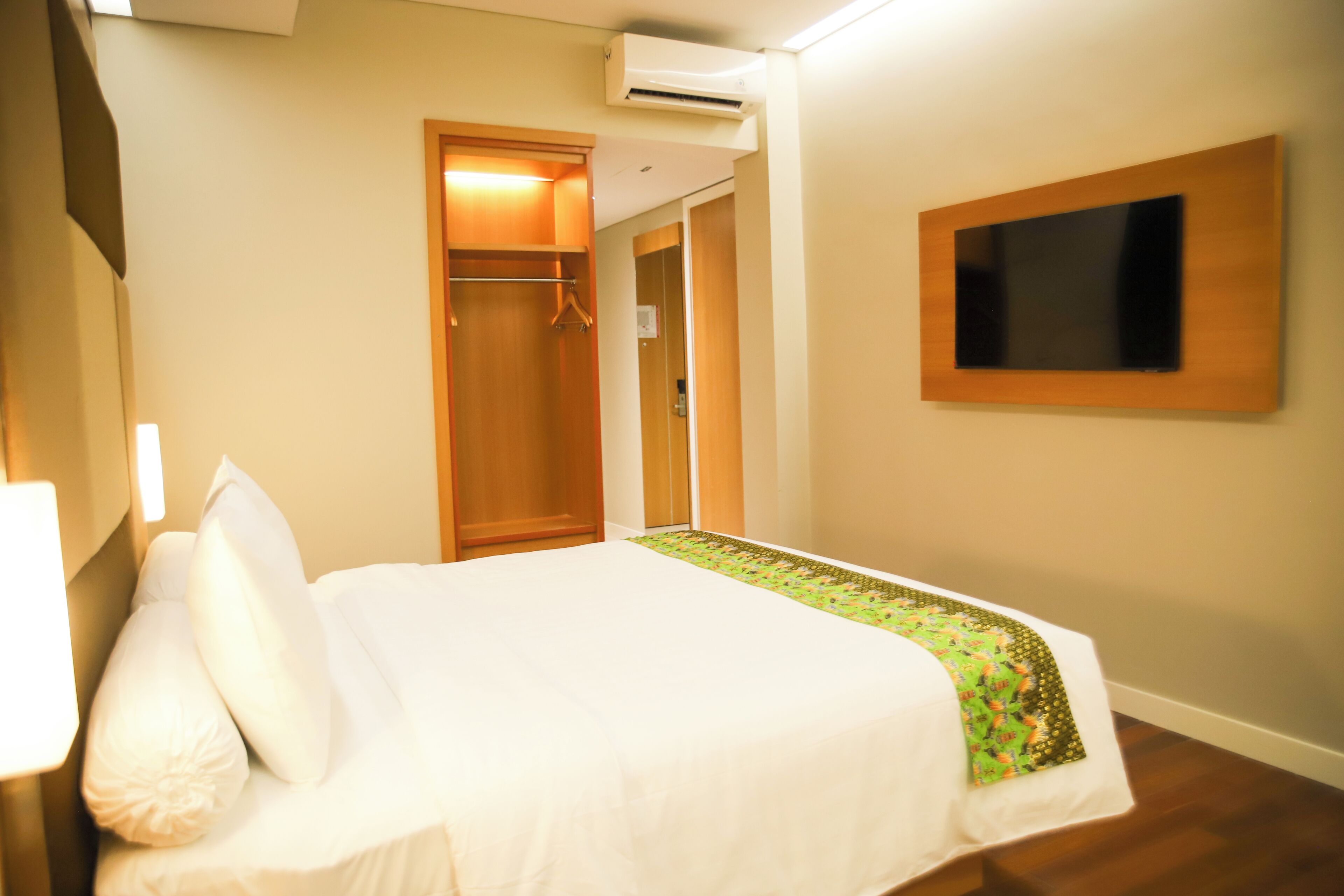Une chambre d’hôtel équipée d’un lit, d’une armoire, d’un téléviseur fixé au mur et d’un appareil de climatisation.