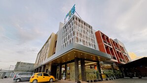 A modern hotel with a prominent entrance, a yellow car parked in front, and a clear sky. - Front One Hotel Papua Lestari (Timika)