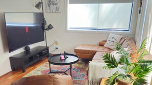 A living room with a TV, sofa, bean bag, coffee table, and a potted plant. - Quiet, peaceful northcote 1 bedroom unit (Northcote)