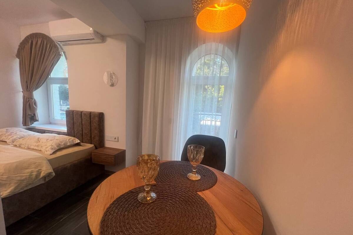 A bedroom with a bed, bedside table, and a window with curtains.