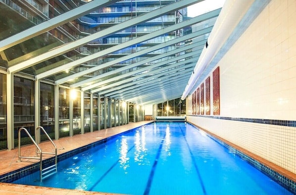 An indoor swimming pool with glass walls and a modern architectural design.