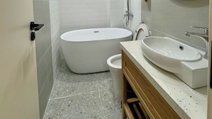 Ein modernes Badezimmer mit einer freistehenden Badewanne, einem Waschbecken mit Spiegel und einer Duschbrause.