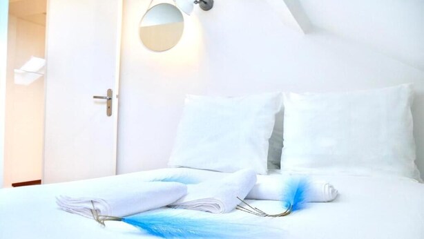 Un letto rifatto con lenzuola bianche, un asciugamano piegato e un paio di occhiali sul letto.