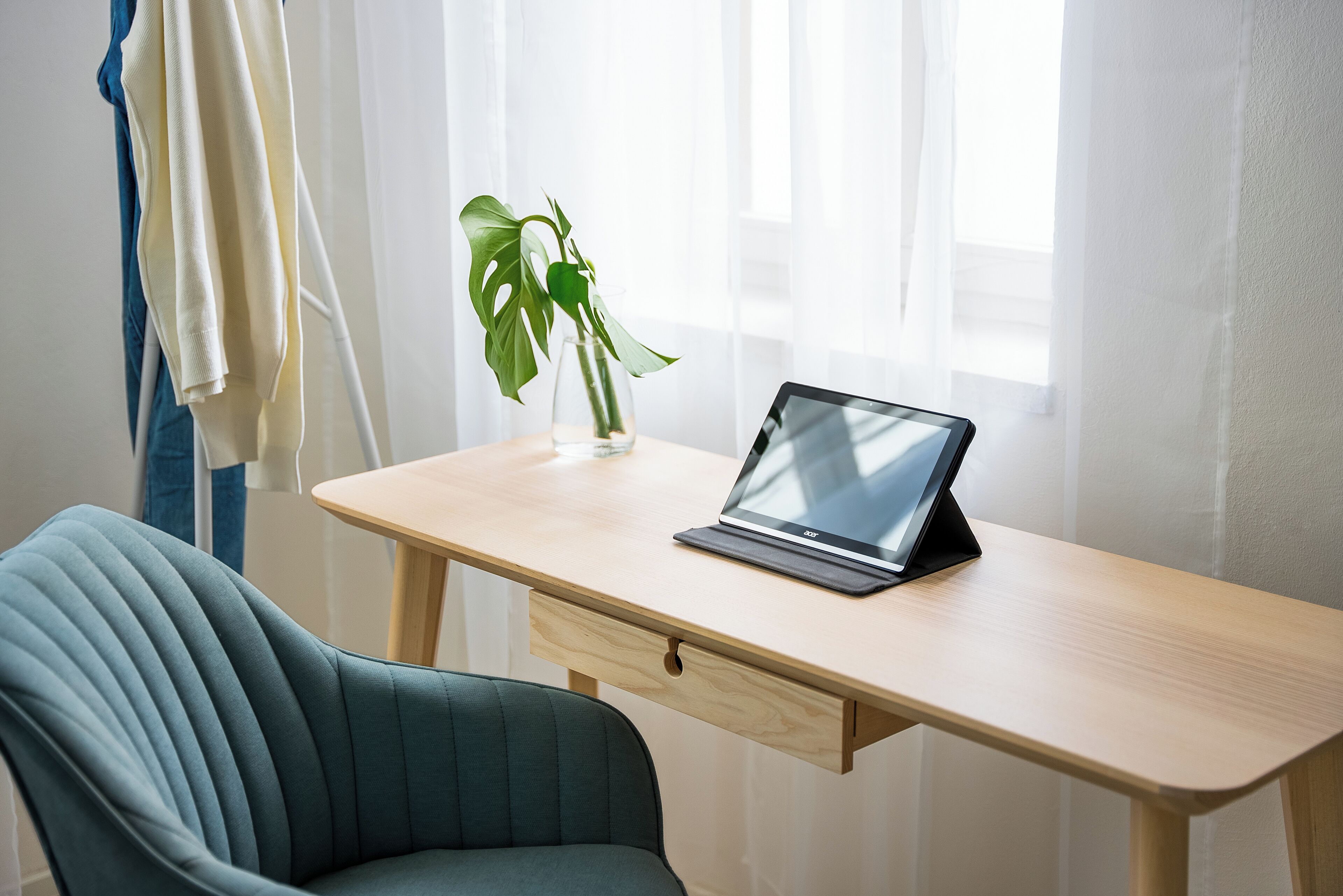 Un espacio de trabajo moderno con una computadora portátil sobre un escritorio de madera, una silla verde y una planta en maceta.