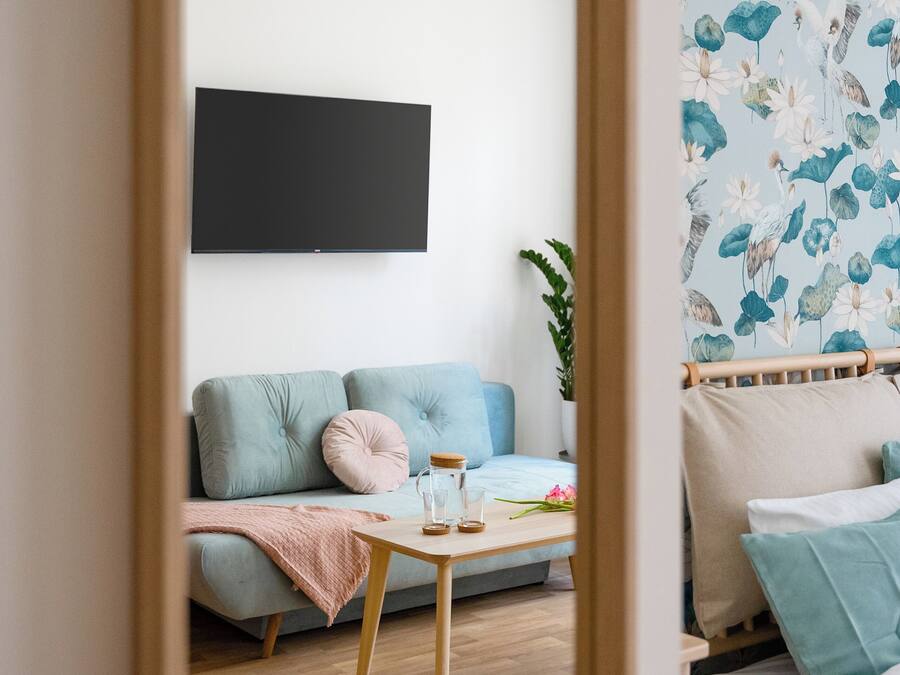 A modern living room with a sofa, a coffee table, and a bed with a floral wallpaper.