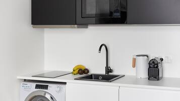 Una cocina equipada con lavadora, microondas, pileta y cafetera.