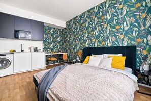 A bedroom with a bed, a washing machine, and a kitchenette. - Enjoy Downtown Boutique Apartments 13 by goodnite cz (Brno)