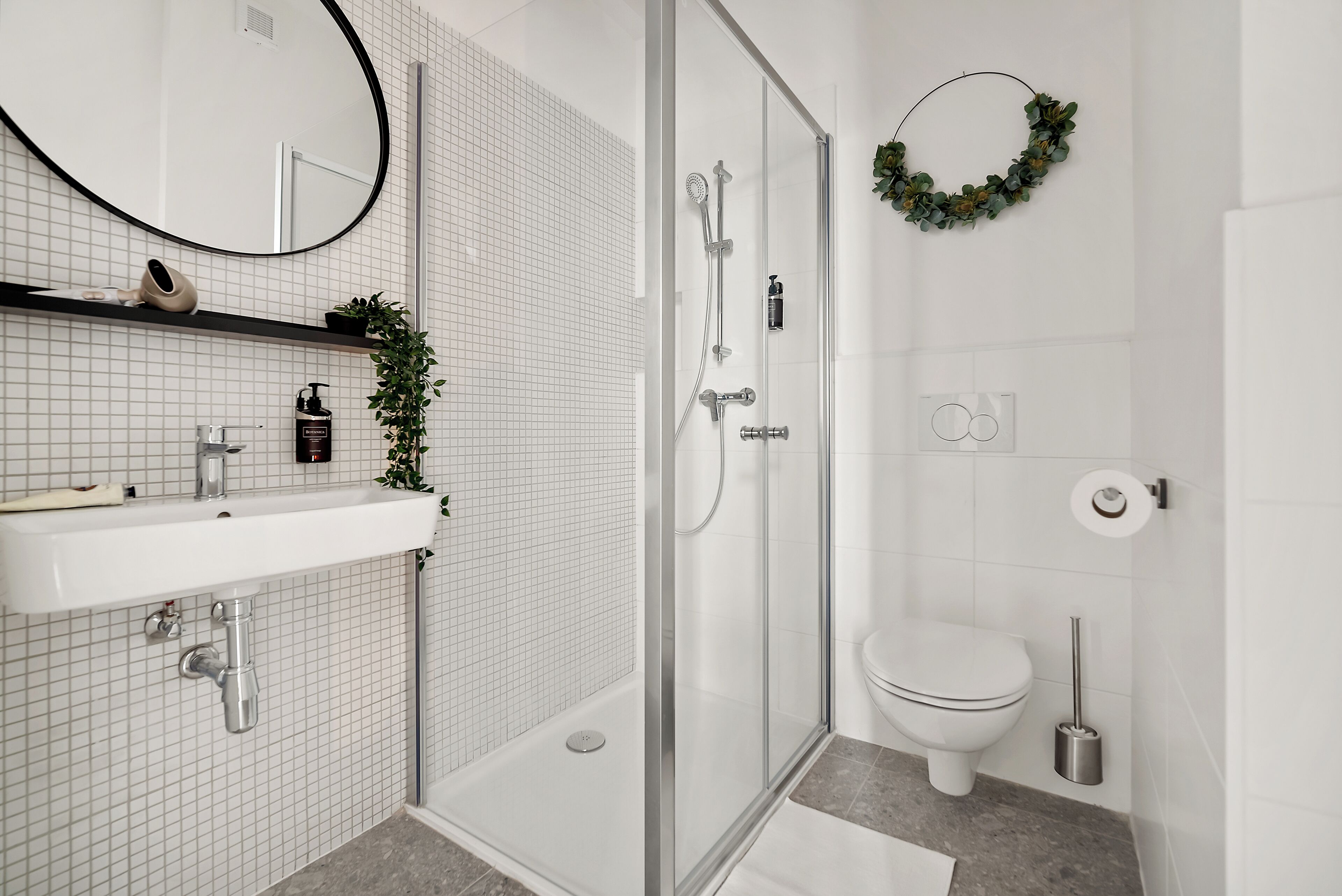 A modern bathroom with a glass-enclosed shower, a white sink with a mirror, and a toilet.