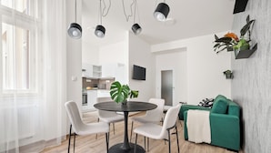 Una sala de estar moderna con comedor, un sofá verde y un televisor montado en la pared.