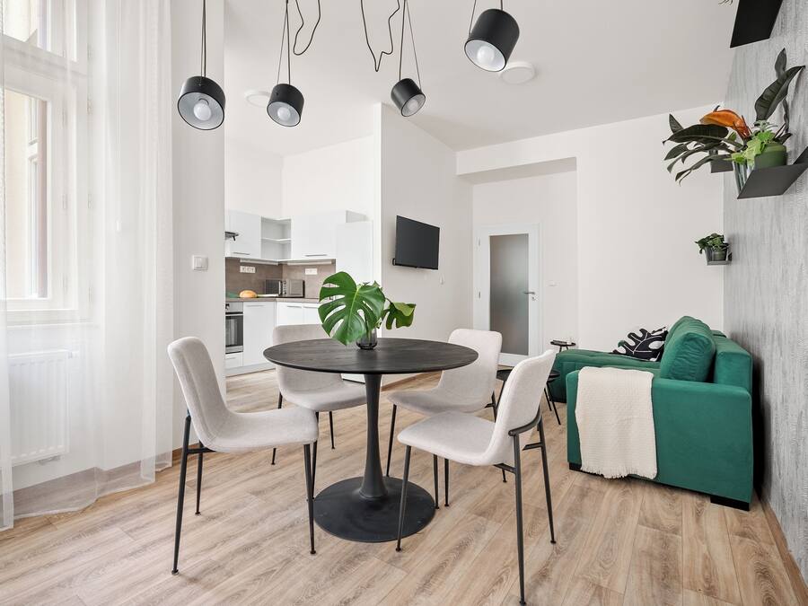 Una sala de estar moderna con comedor, un sofá verde y un televisor montado en la pared.