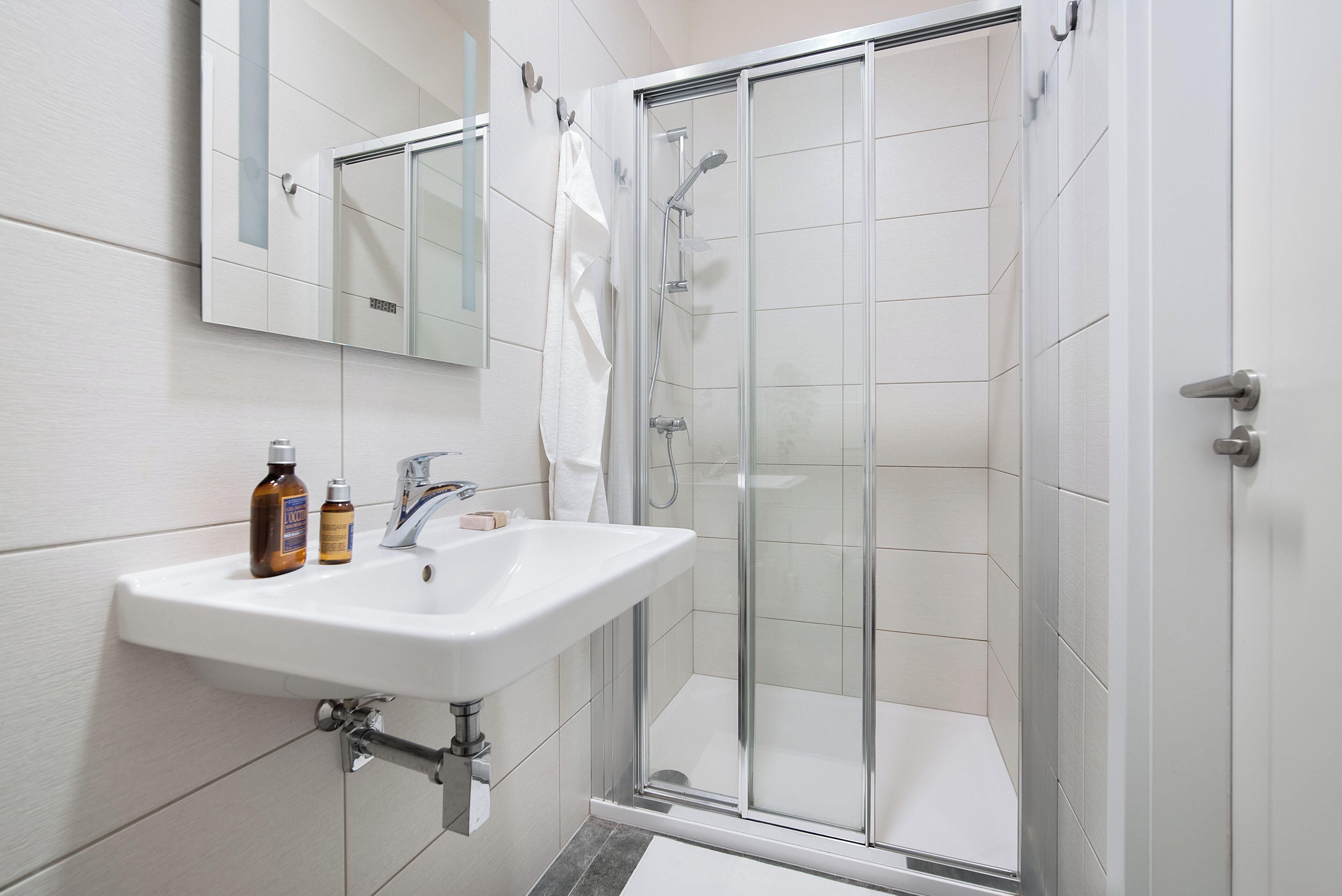 Een moderne badkamer met een wit wastafelmeubel, spiegel en een douchecabine met glazen wanden.