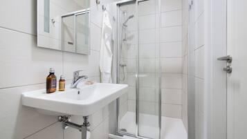 Een moderne badkamer met een wit wastafelmeubel, spiegel en een douchecabine met glazen wanden.