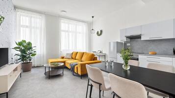 A modern living room with a sofa, coffee table, and dining area.