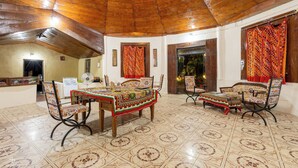 A dining area with a wooden ceiling, tiled floor, and colorful tablecloths.