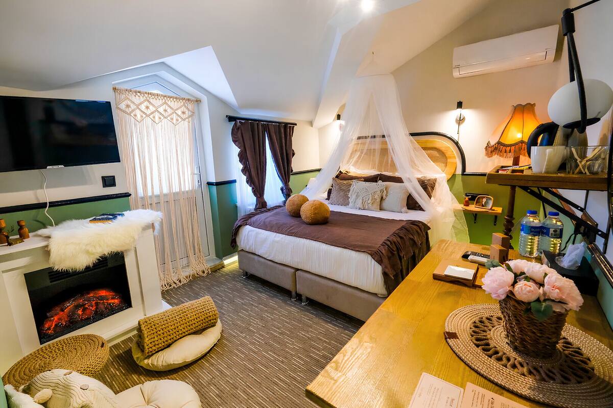 Ein Schlafzimmer mit einem Bett, einem Fernseher, einem Kamin, einem Nachttisch und einem Beistelltisch.