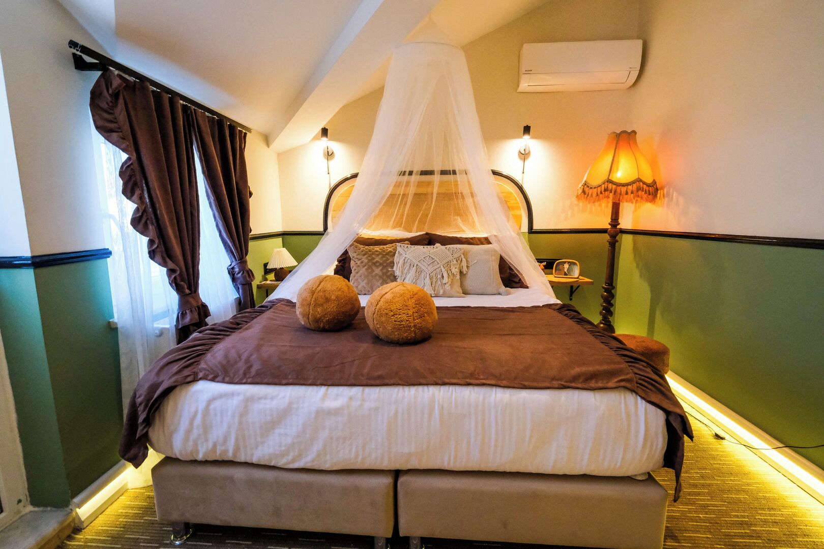 Una habitación de hotel con cama, dosel, lámpara y aire acondicionado.