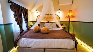 Una habitación de hotel con cama, dosel, lámpara y aire acondicionado.